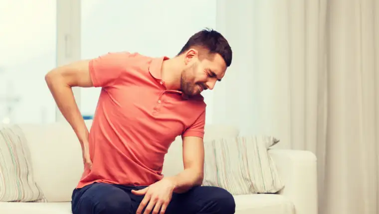 unhappy man suffering from backache at home
