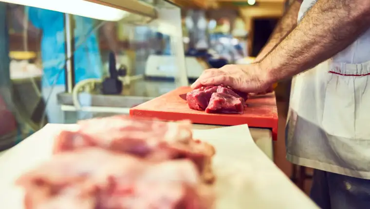 Meat is meat and a man must eat. a butcher at his store.