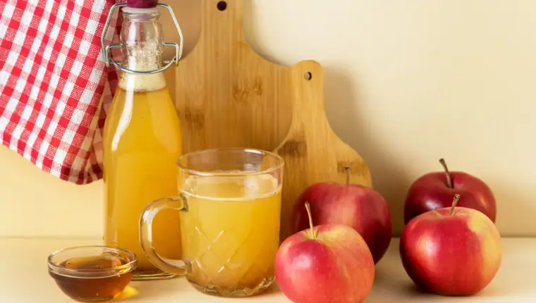 Apple Cider Vinegar in Glass Mug and Bottle with Honey and Cinnamon Red Apples Yellow Background Horizontal