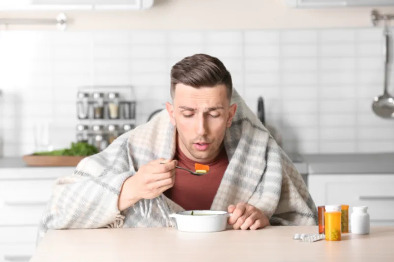 Sick,Young,Man,Eating,Broth,To,Cure,Cold,At,Table