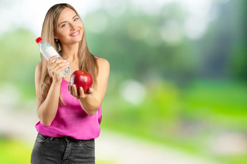 Portrait of happy smiling young beautiful woman eating red apple