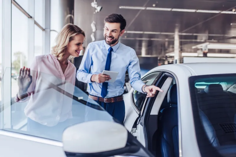 client and salesman looking at new car