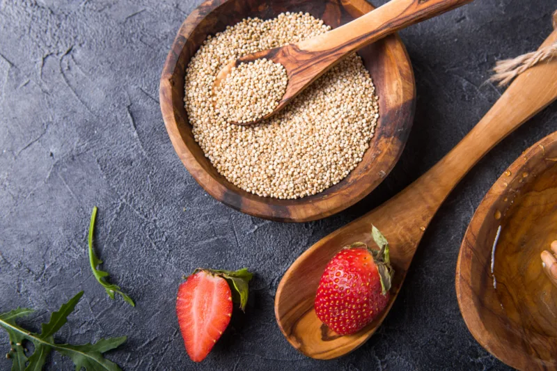 Quinoa White grains in a wooden bowl and spoon with strawberry,