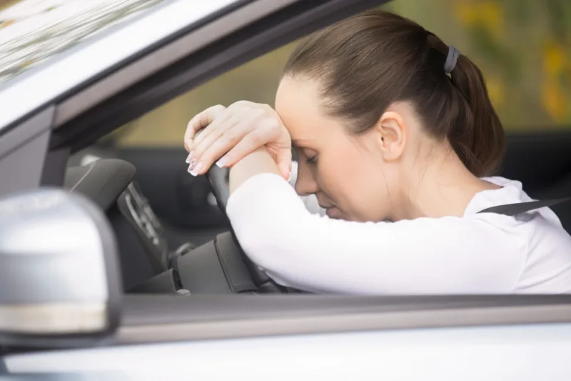 Young woman talking on her phone driving a car