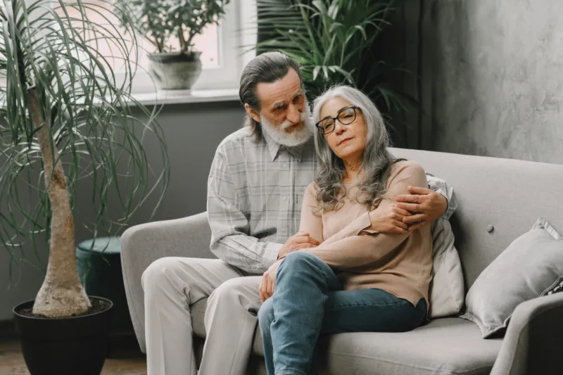 Senior couple in casual clothes sitting on couch in living room