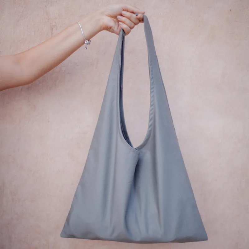 the girl holds in her hand a gray fabric bag on the background of the set. the shopper for conscious shopping. zero waste concept