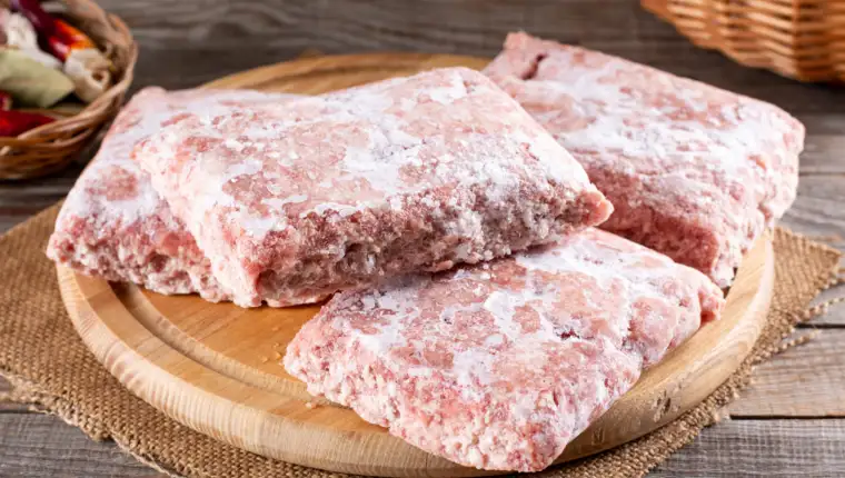Frozen ground meat, minced pork on a wooden board. Ground chicken inclusive backs, necks, liver and heart. Frozen food. Concept for raw food diet for cats, dogs and pets.