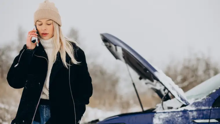 Young woman calling on the phone after her car brokedown in winter season