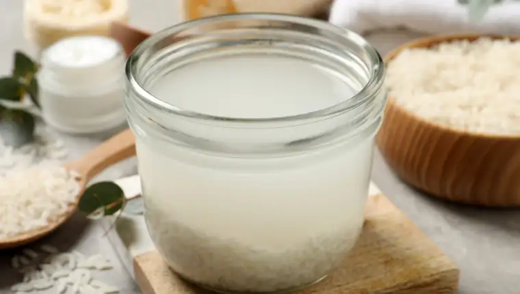 Glass jar with rice soaked in water on light grey table