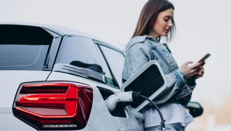 Woman charging her electric car with charging pistol