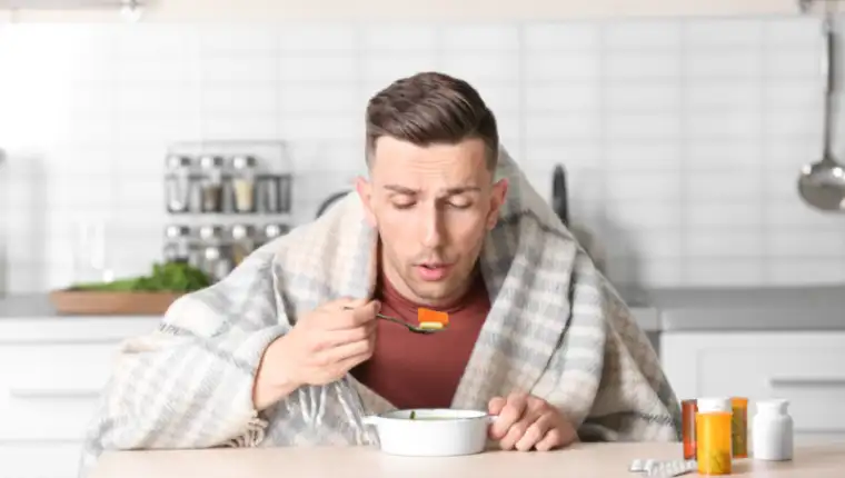 Sick,Young,Man,Eating,Broth,To,Cure,Cold,At,Table