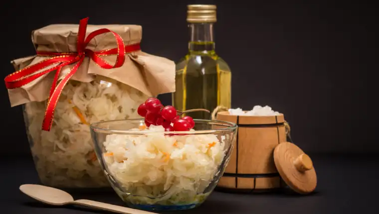 Fermented cabbage with herbs and spices in glass bowl and jar on the black background