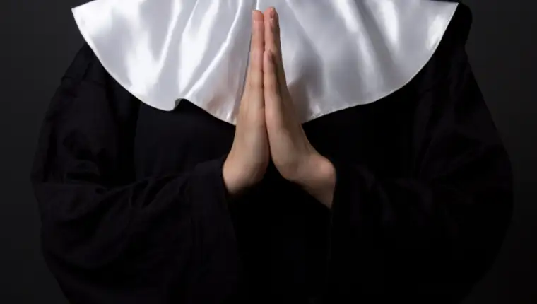 religion concept - hands of woman nun praying over grey