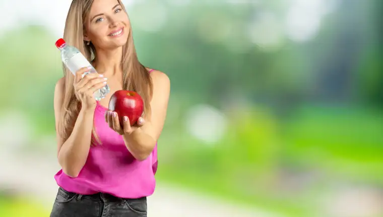 Portrait of happy smiling young beautiful woman eating red apple