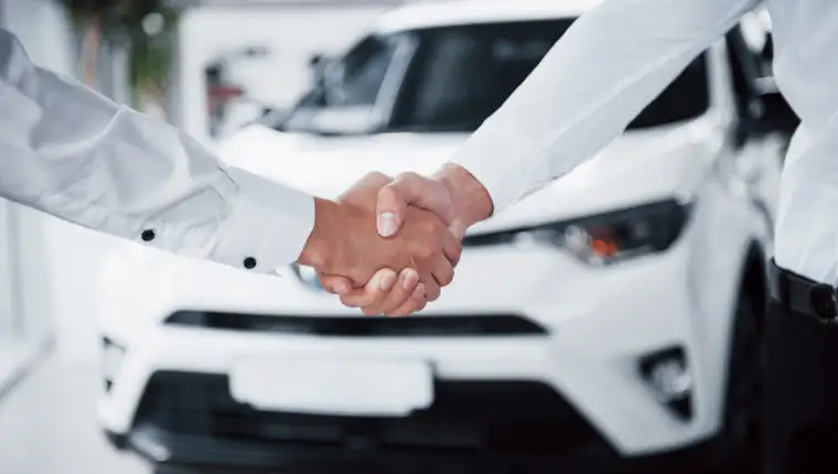 Close up of sales manager in black suit selling the car to the customer