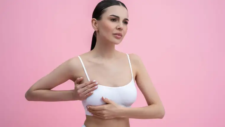 Young woman in white bra examining her breast with her hand