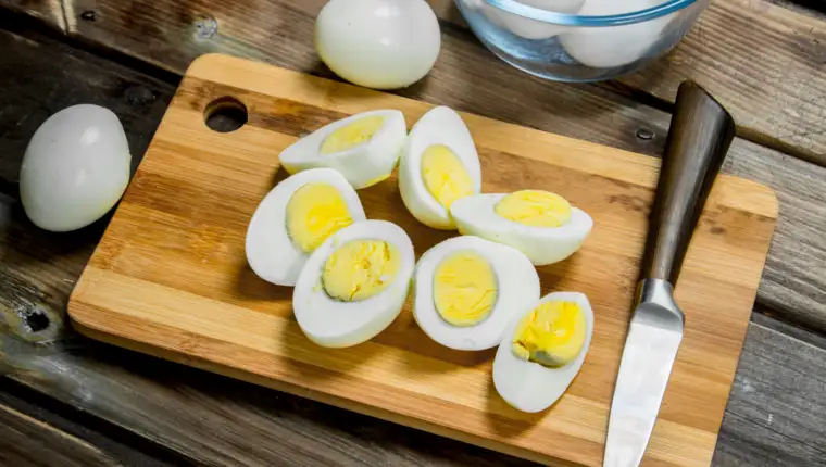Sliced boiled eggs on cutting board.