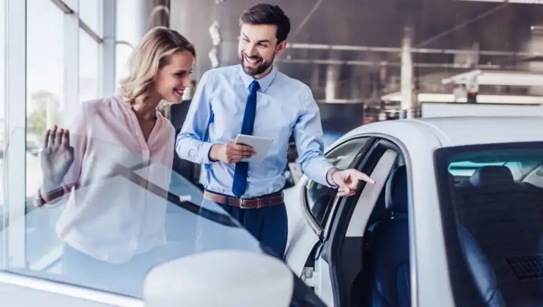 client and salesman looking at new car