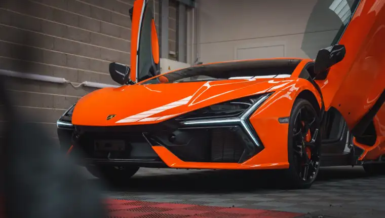 Orange Lamborghini Revuelto with Scissor Doors Open in Indoor Setting