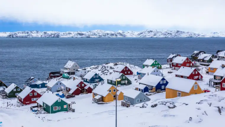 Colorful inuit houses among rocks and snow at the fjord in a sub