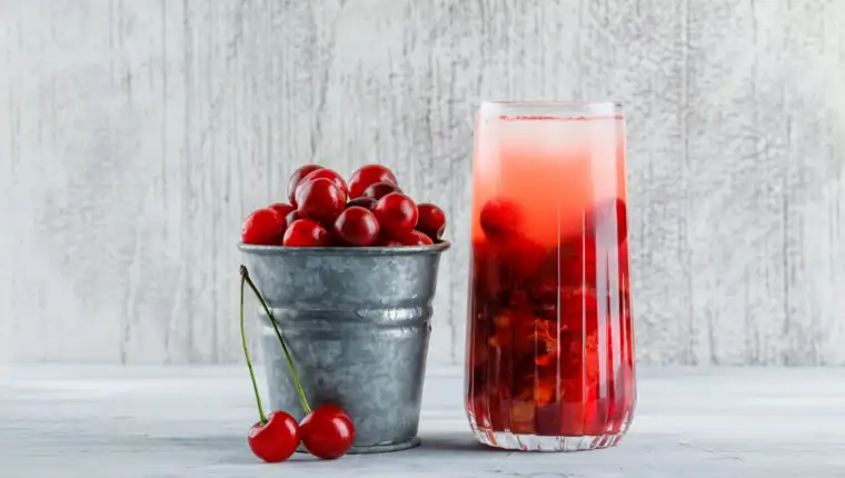 Cherry cocktail in a jug with cherries side view on a grungy background