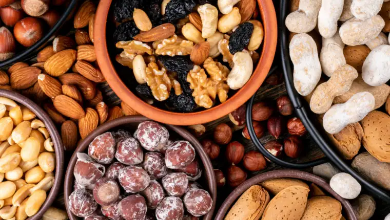 Set of pecan, pistachios, almond, peanut, cashew, pine nuts and assorted nuts and dried fruits in a mini different bowls and black pan. top view.