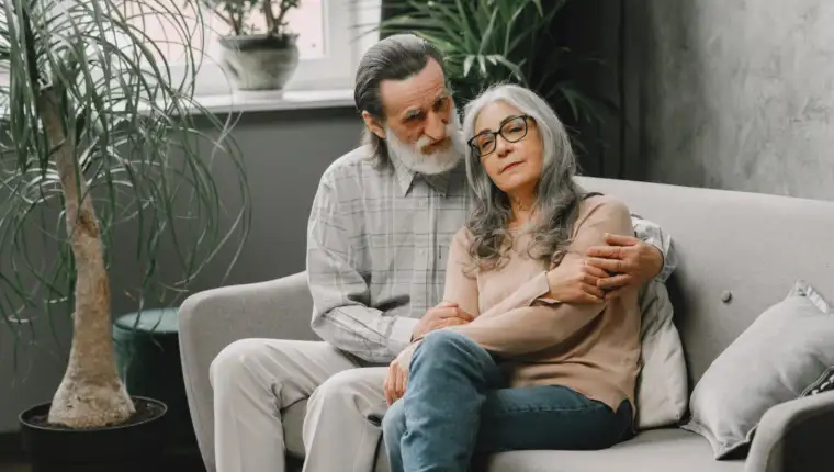Senior couple in casual clothes sitting on couch in living room