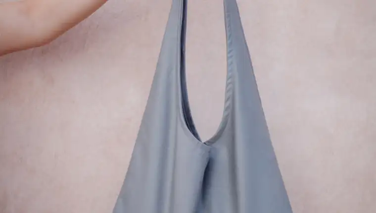 the girl holds in her hand a gray fabric bag on the background of the set. the shopper for conscious shopping. zero waste concept