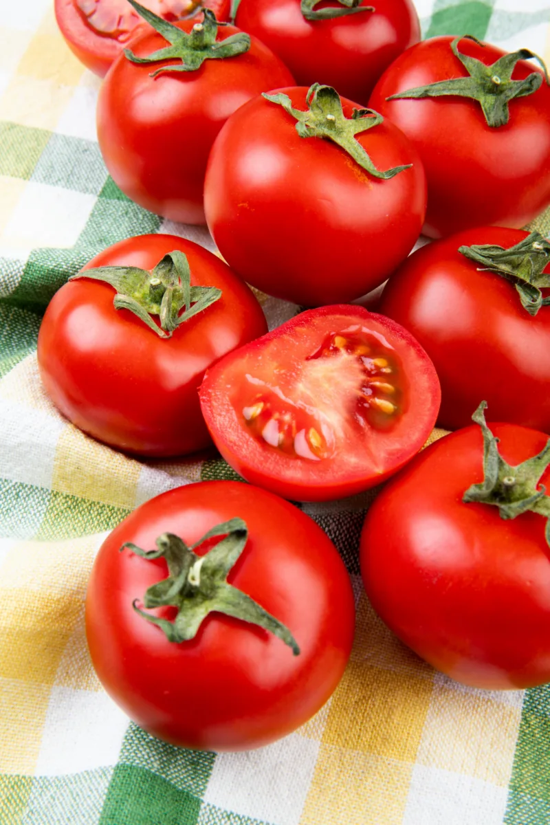side view of cut and whole tomatoes on plaid cloth background