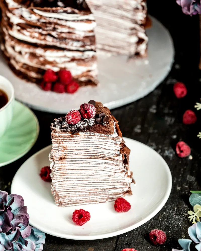 chocolate crepe cake decorated with chocolate and raspberries