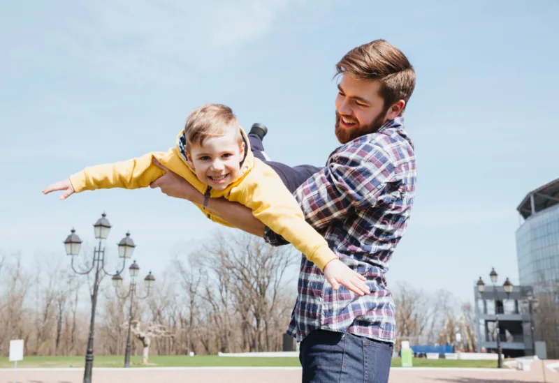 Young smiling father and his little son playing together in a city park