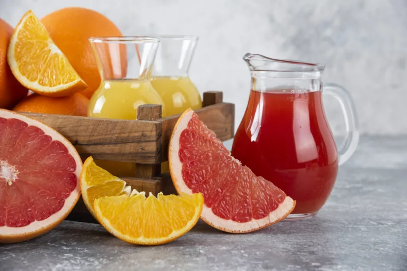 Glass pitchers of grapefruit juice with slices of orange fruits