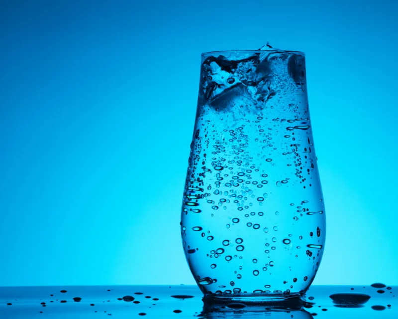 Soda mineral water in glass with ice, bubbles and droplets on th
