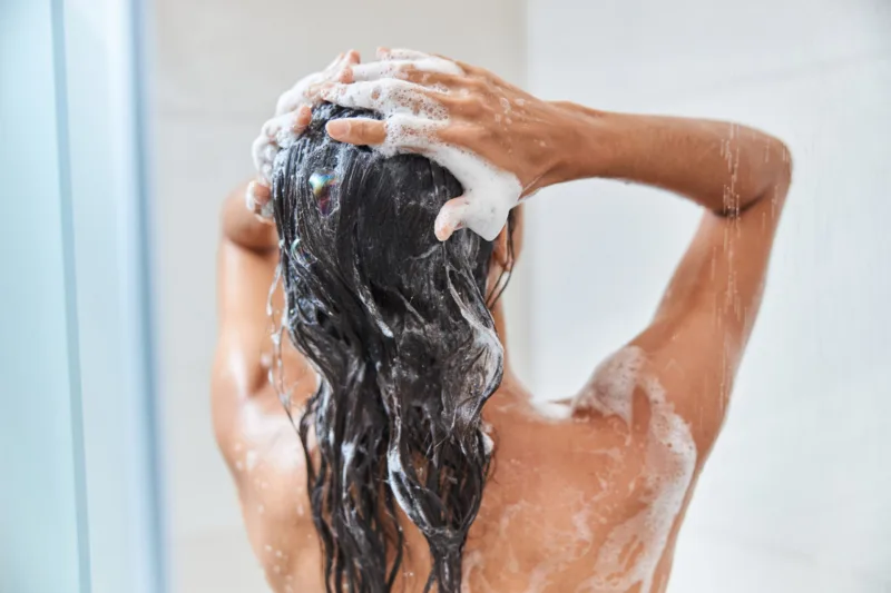 Young woman washing her hair in shower