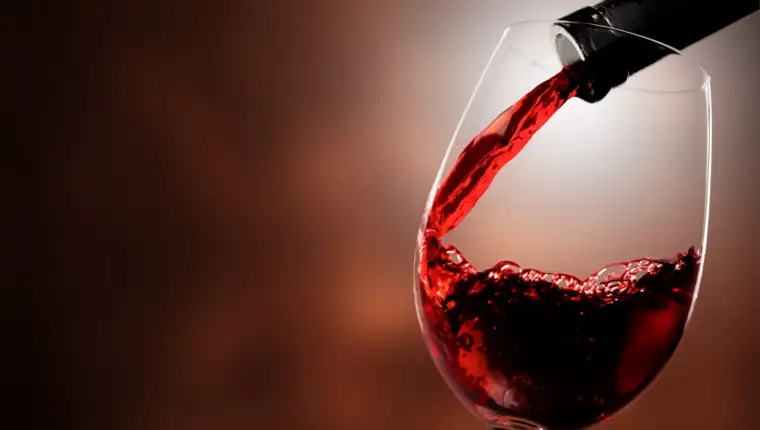 Red wine being poured in wineglass, closeup