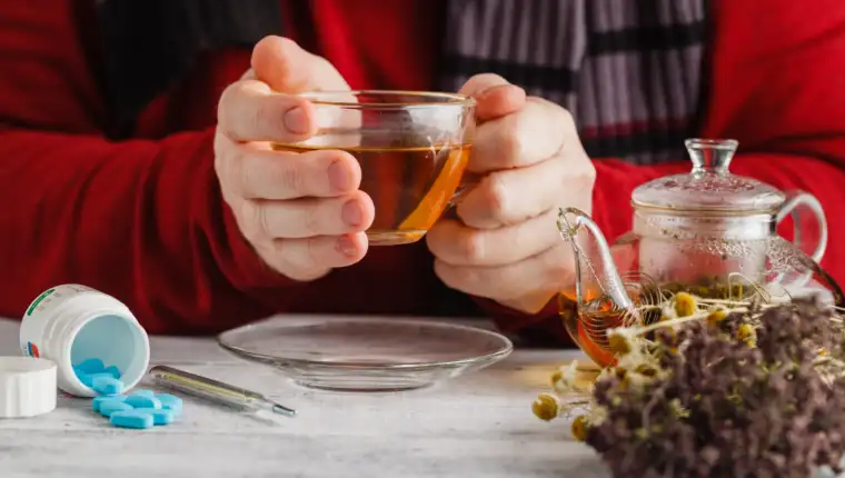 Hot tea against fever. Male looks the temperature on the thermom