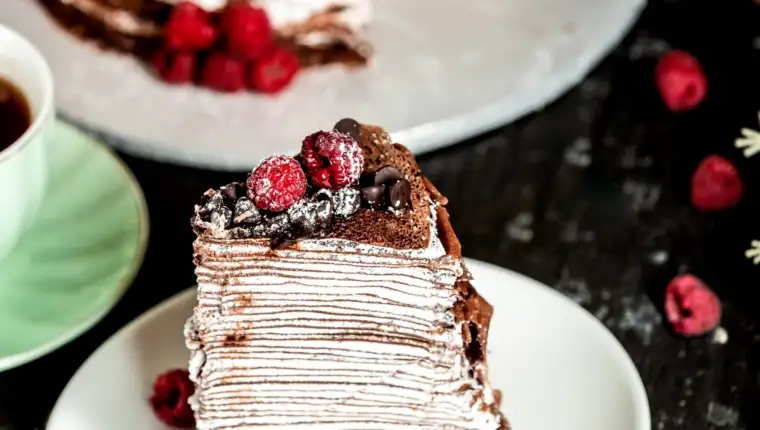 chocolate crepe cake decorated with chocolate and raspberries