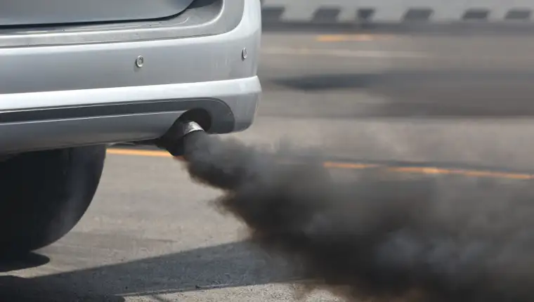 Air pollution from vehicle exhaust pipe on road.