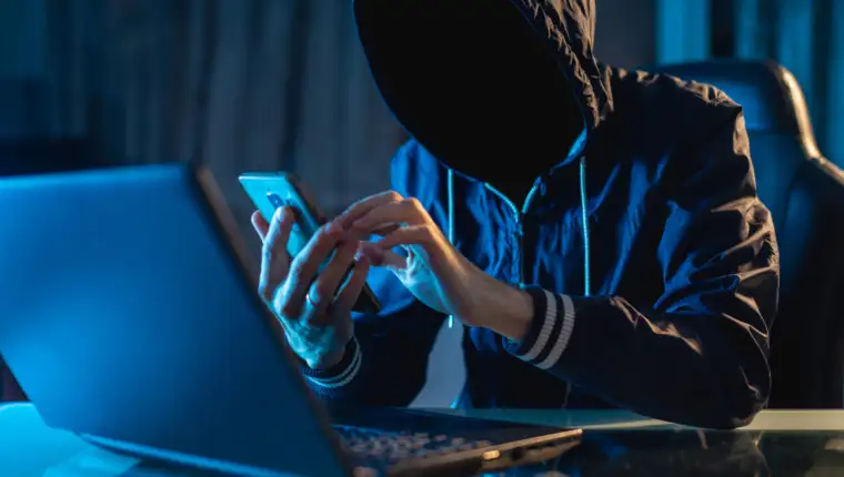 Anonymous hacker programmer uses a laptop to hack the system in the dark. Concept of cybercrime and hacking database