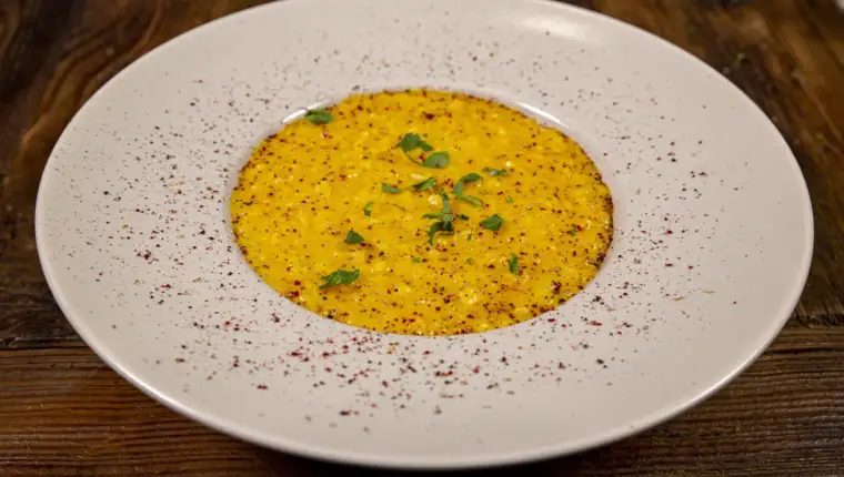 Close up and over a plate of risotto with saffron, white plate on a rustic  table