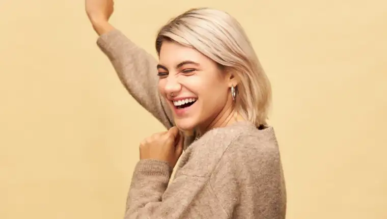 Positive human emotions and feelings. Joyful happy young woman with bob hairstyle and nose ring celebrating success, laughing and dancing, having cheerful facial expression, posing isolated in studio