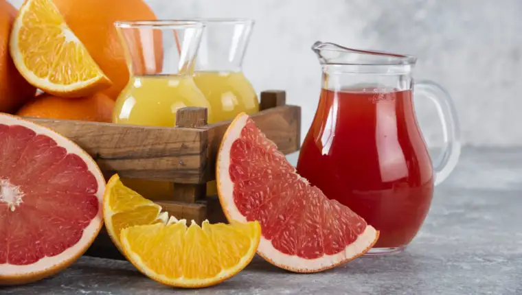 Glass pitchers of grapefruit juice with slices of orange fruits