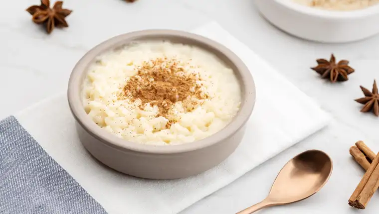 Creamy rice pudding with cinnamon in bowl on white marble table