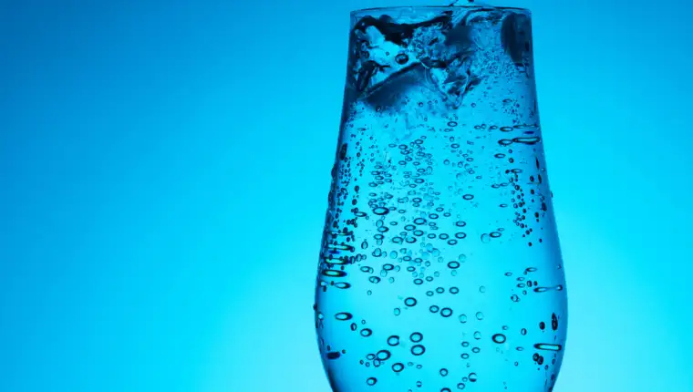 Soda mineral water in glass with ice, bubbles and droplets on th
