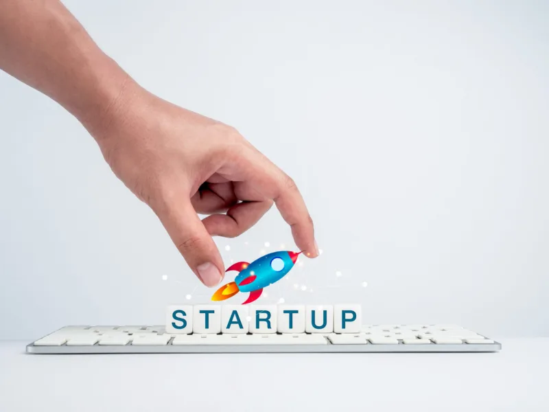 Startup concept. Hand holding rocket on white dice blocks.