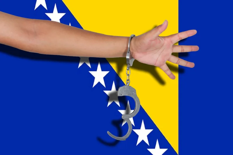 handcuffs with hand on Bosnia Herzegovina flag