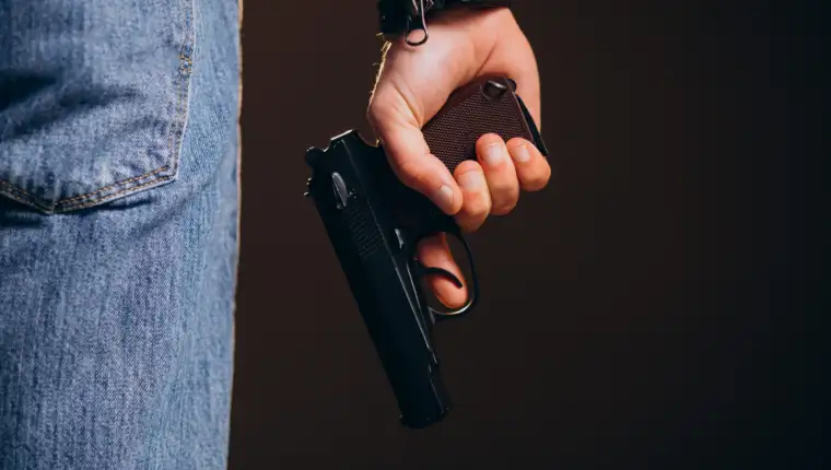 Handsome man actor posing in studio with weapon