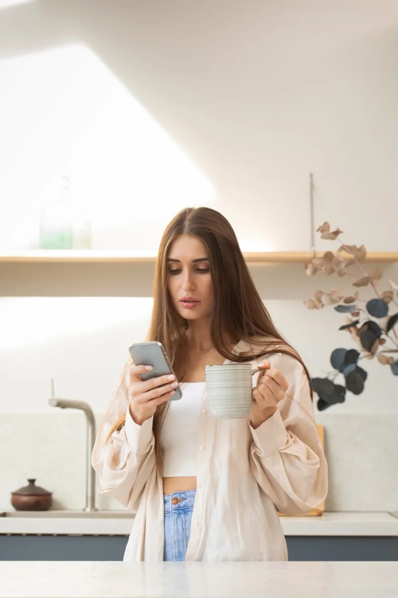 A young brunette woman uses her phone while making online purchases. Surfing the Internet
