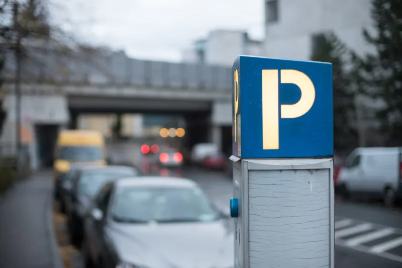 Parking in midtown: parking machine, evening scenery and cars