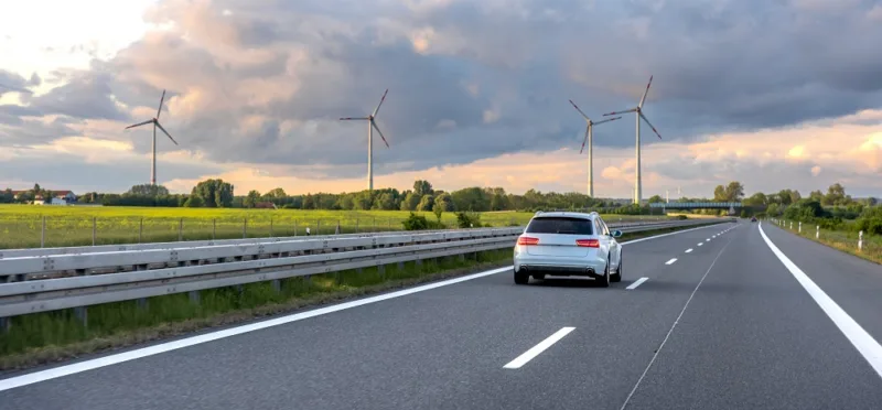 Car on highway. Wind turbines. Renewable energy